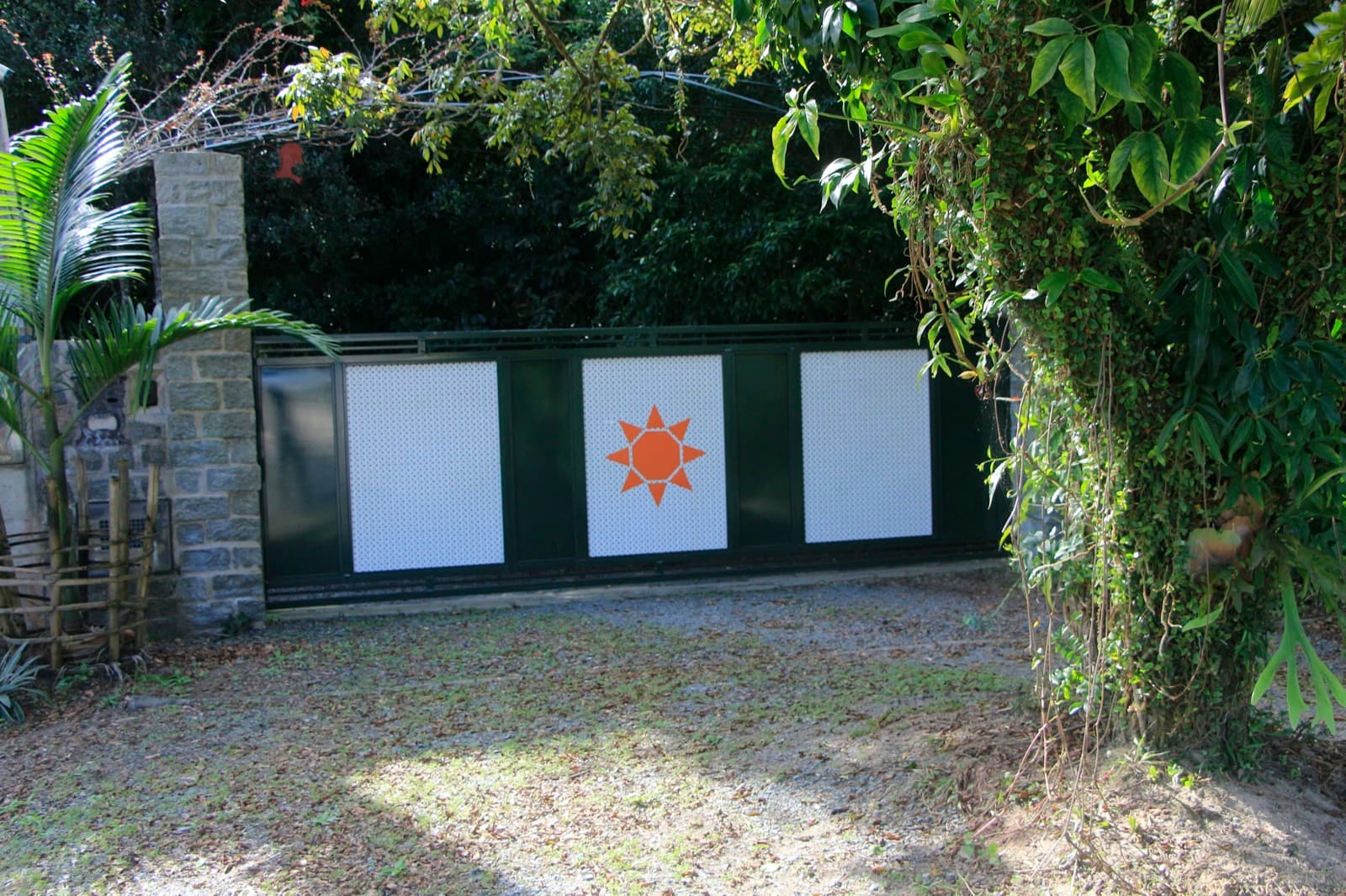 Portão com símbolo do sol entre as árvores